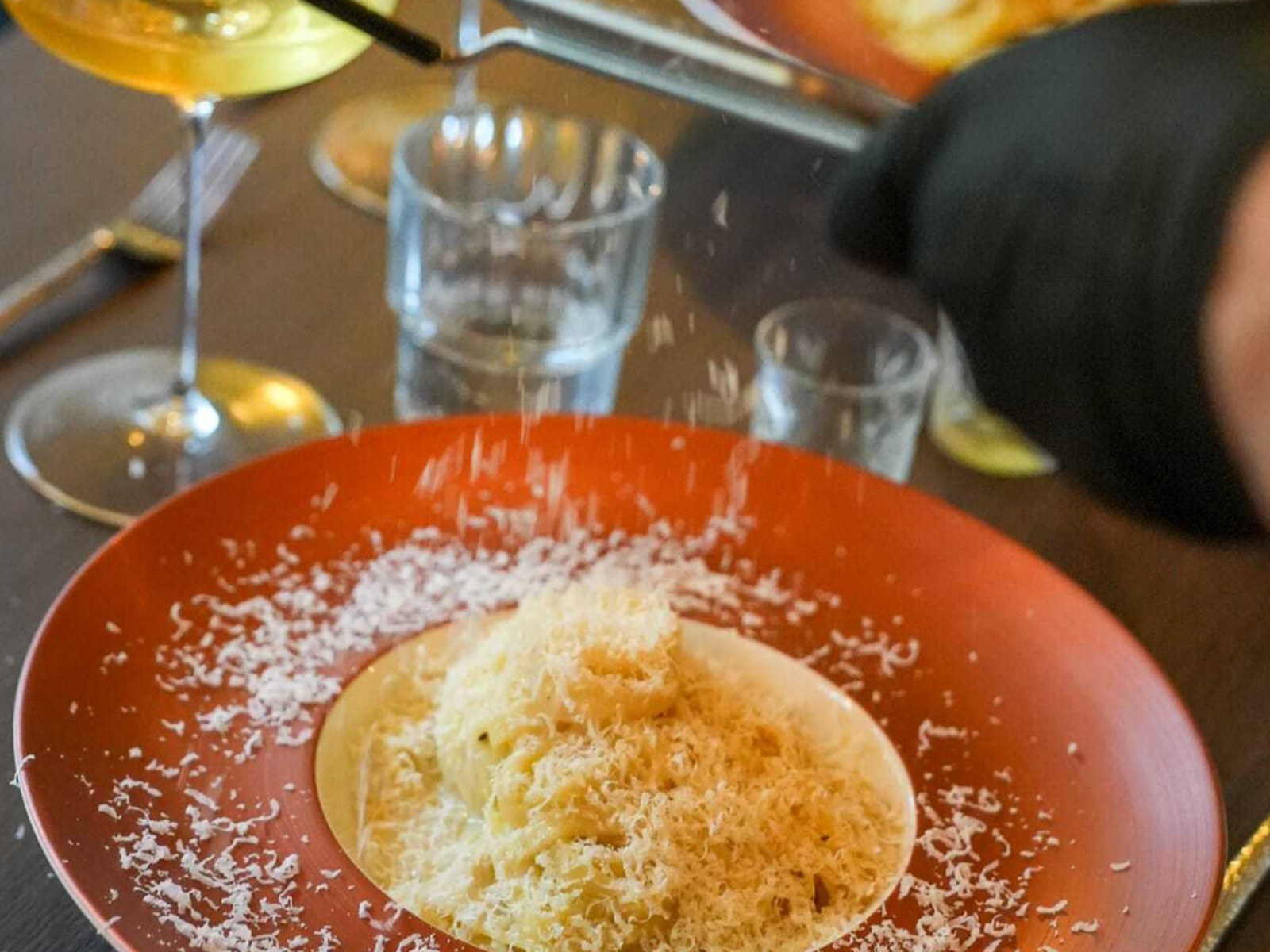 Verse pasta met geraspte kaas en een glas witte wijn bij Da Marlotti